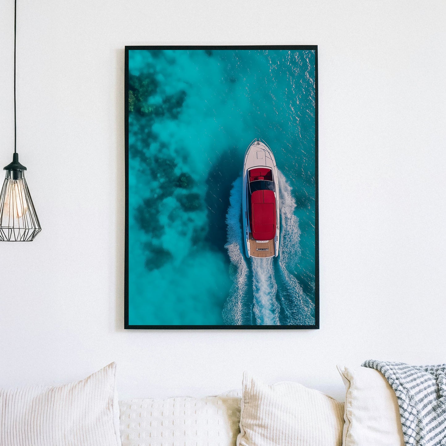 Aerial view of a white yacht with a red canopy cruising through turquoise ocean waters, leaving a foamy wake.