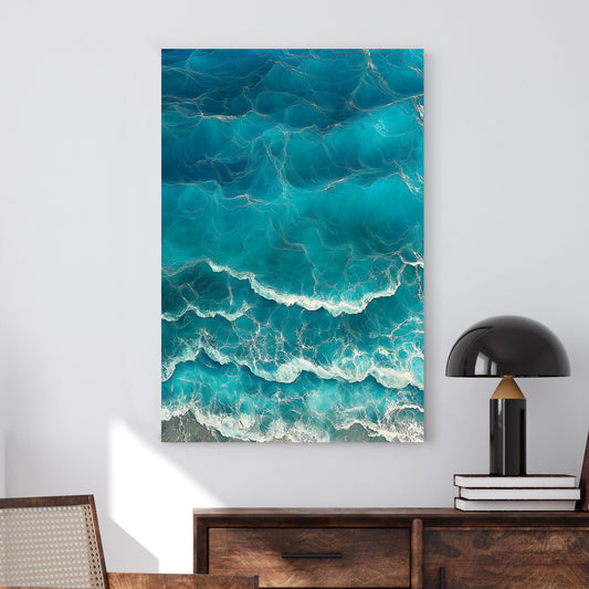 Aerial view of ocean waves rolling onto the shore, featuring deep blue hues and white foamy textures.