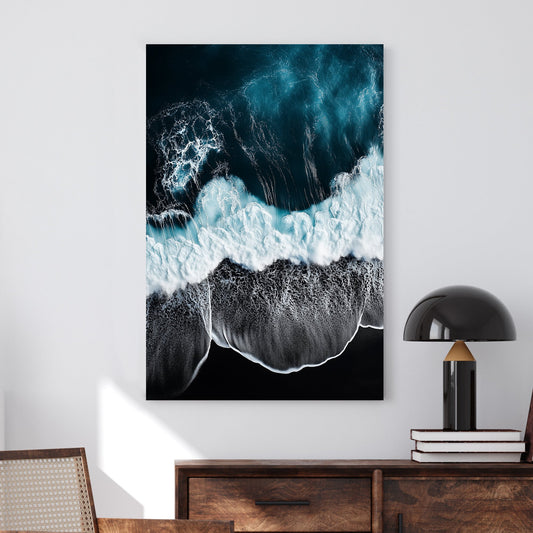 Aerial ocean wall art with deep blue waves crashing onto a black sand beach.