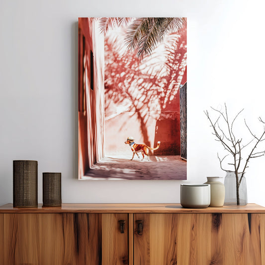 Stylish dog wearing a hat walking through a sunlit alley with palm shadows on pink walls