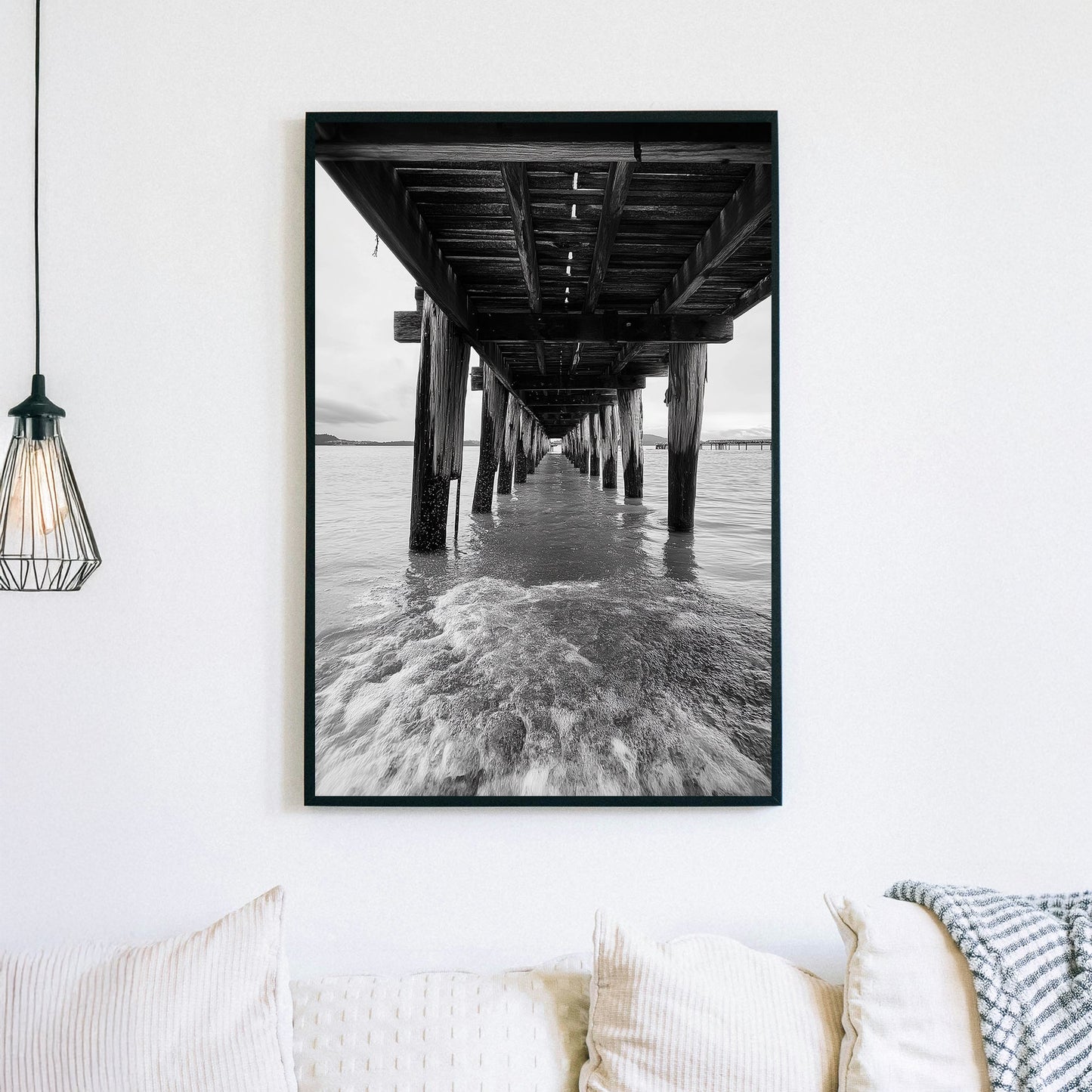 black and white wall art photography of ocean waves under wooden pier with vanishing point perspective