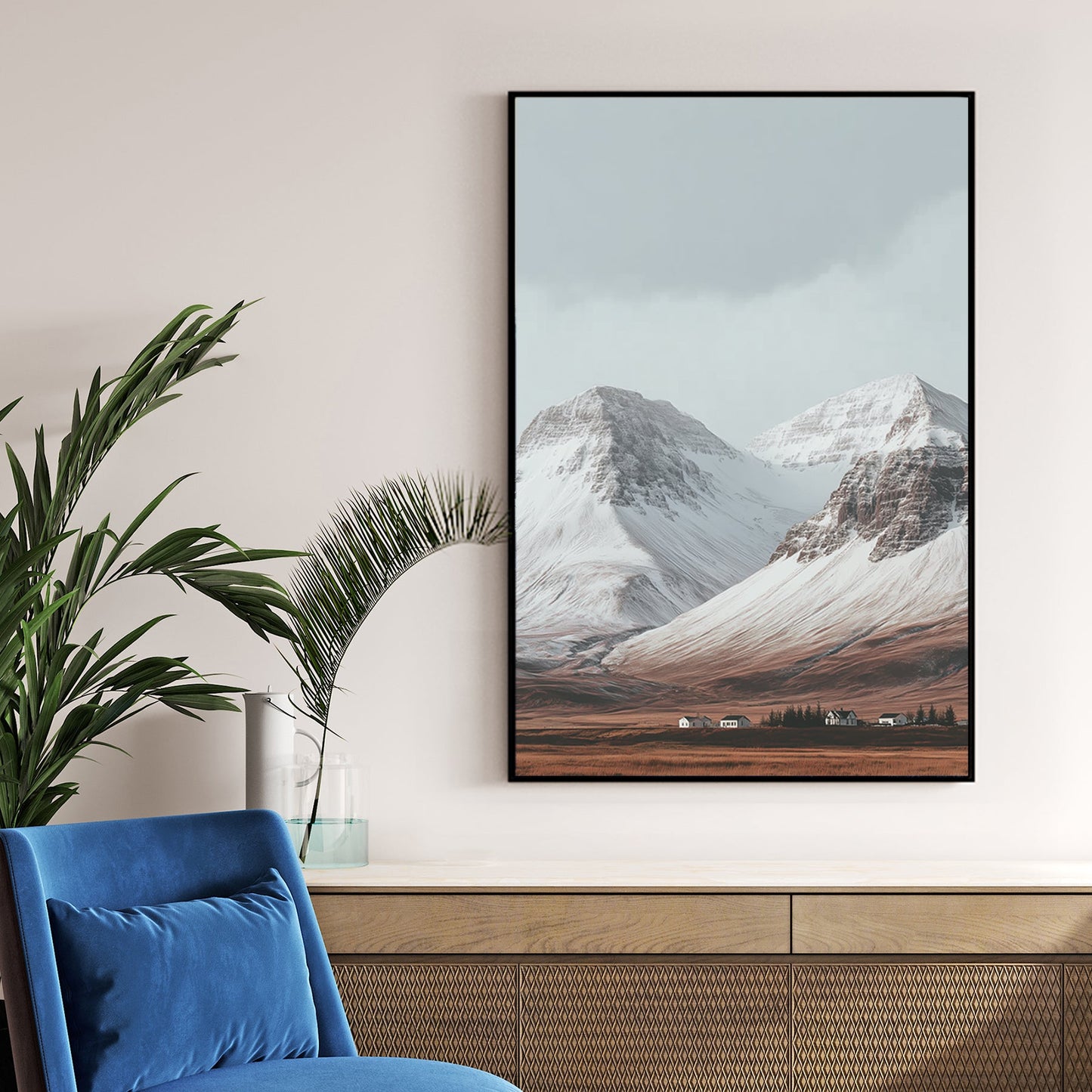 Snowy mountain landscape with cabins on a golden plain beneath grey skies