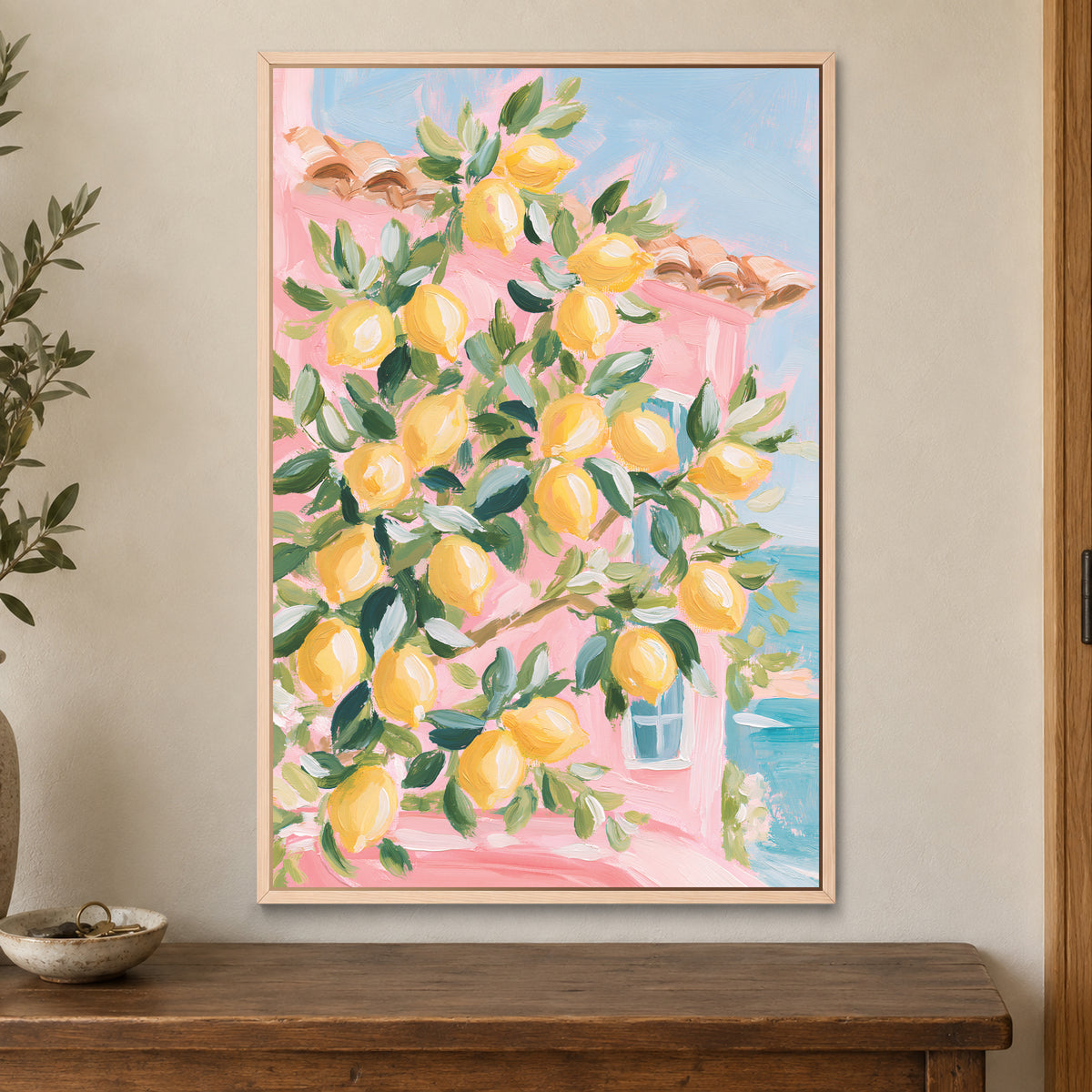 Lemon Tree and Blue Shutters framed canvas in a natural wood floating frame on a cream wall above a wooden sideboard beside a door frame