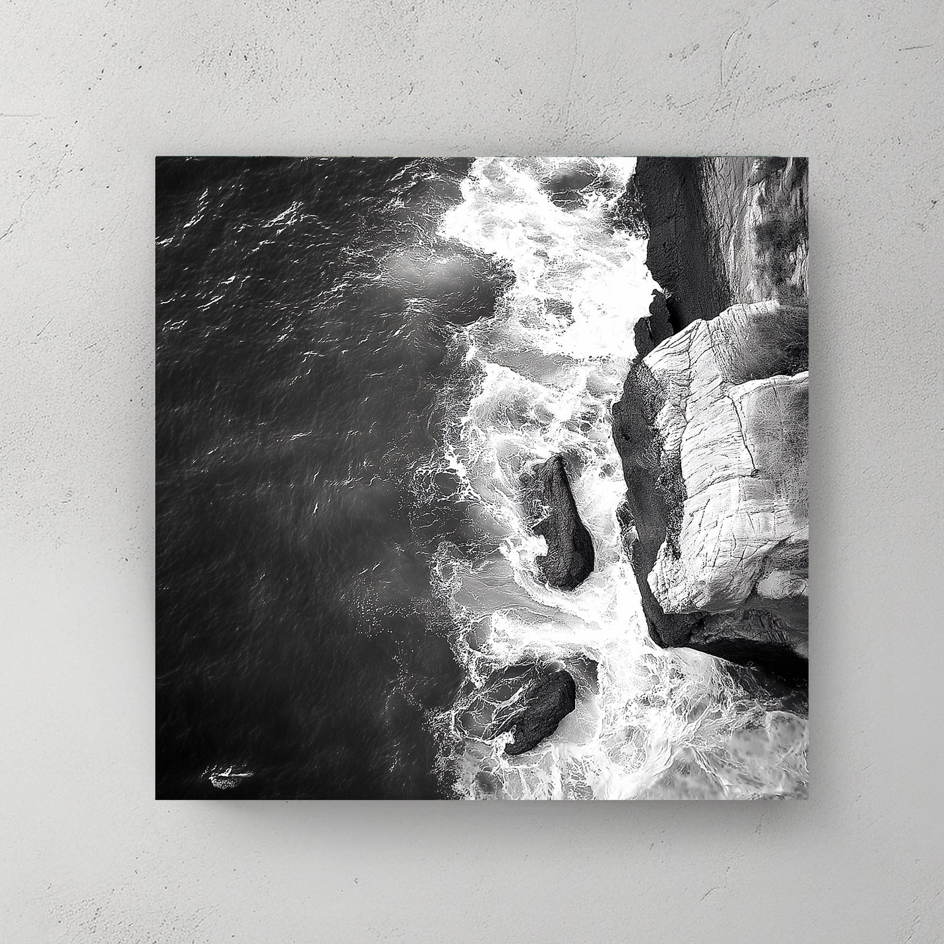 Black and white image of waves crashing against rocky cliffs, creating a dramatic coastal scene.