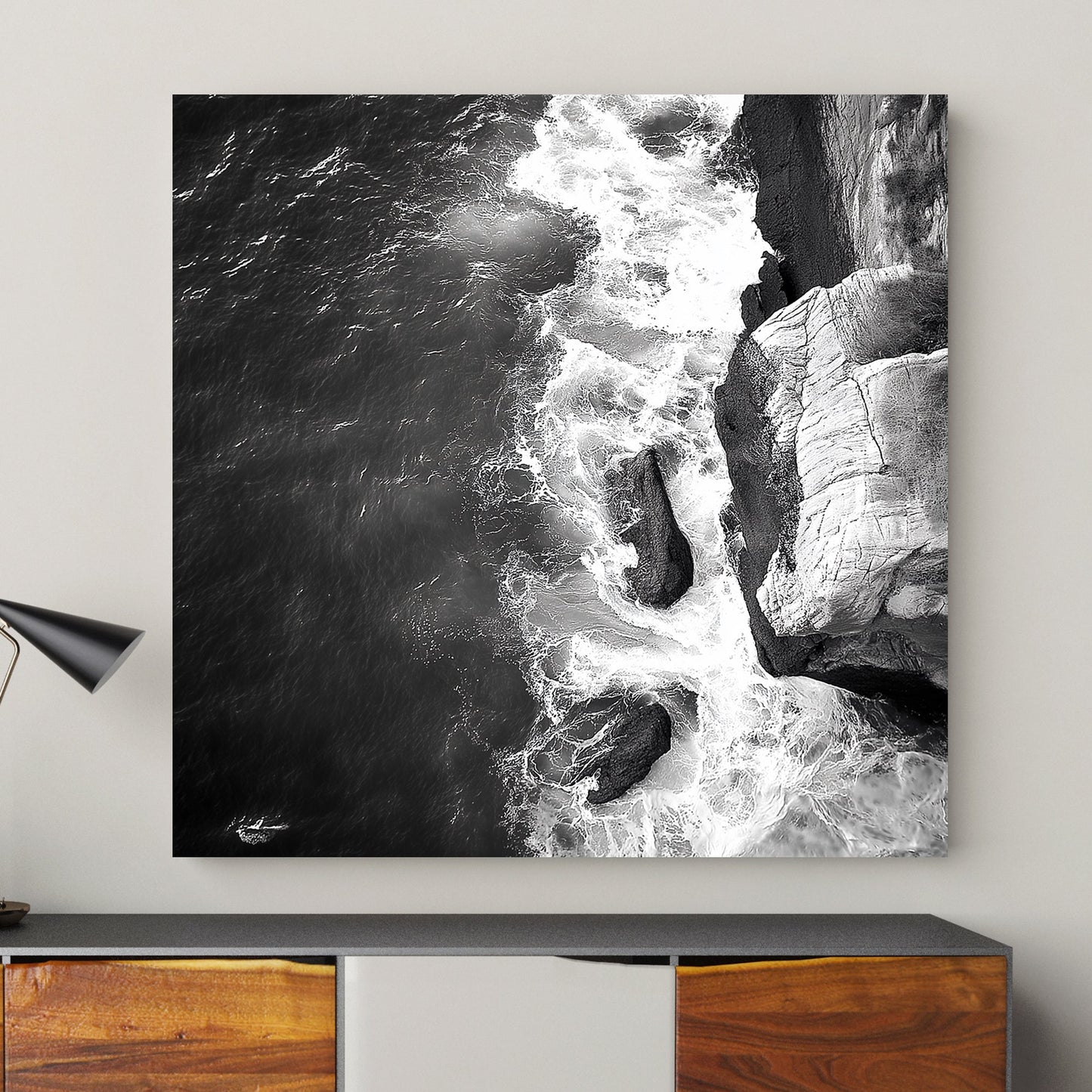 Black and white image of waves crashing against rocky cliffs, creating a dramatic coastal scene.