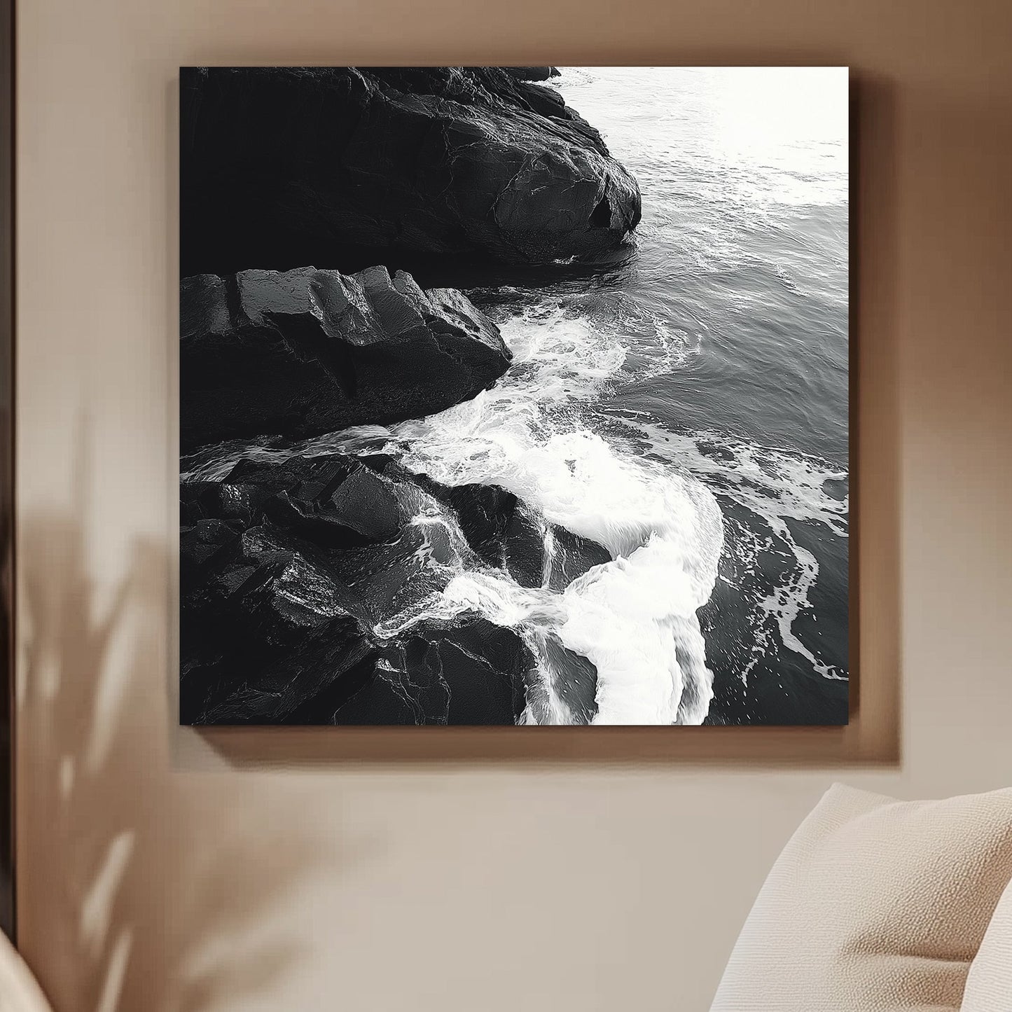 Black and white image of ocean waves splashing against rugged rocks along the shoreline.