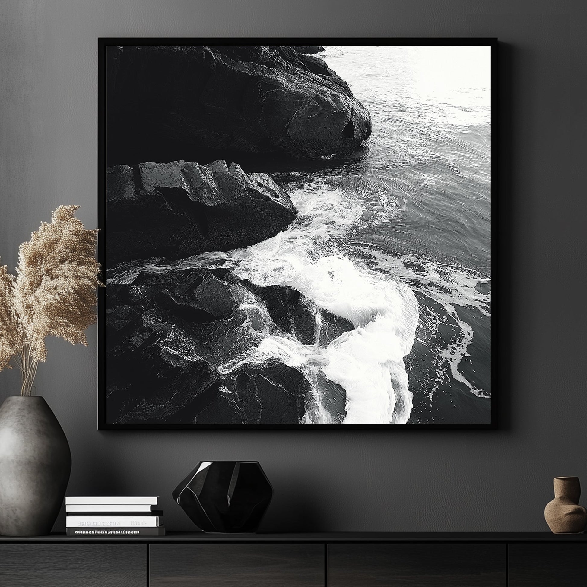 Black and white image of ocean waves splashing against rugged rocks along the shoreline.