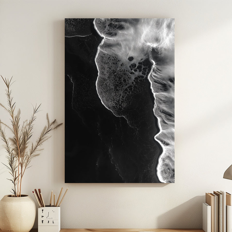Abstract black-and-white aerial view of ocean waves meeting the shore, showcasing organic patterns and textures.