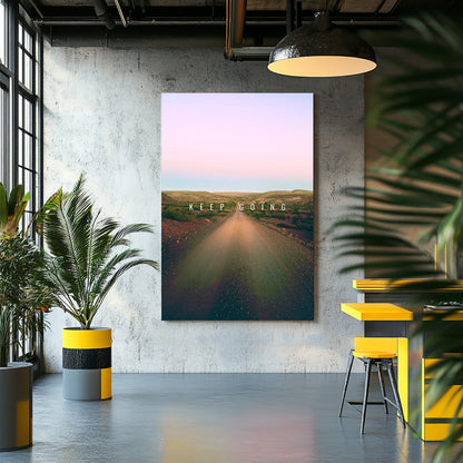 A metal wall art print of a peaceful dirt road stretches into the horizon under a gradient pastel sky, featuring the motivational text "Keep Going."