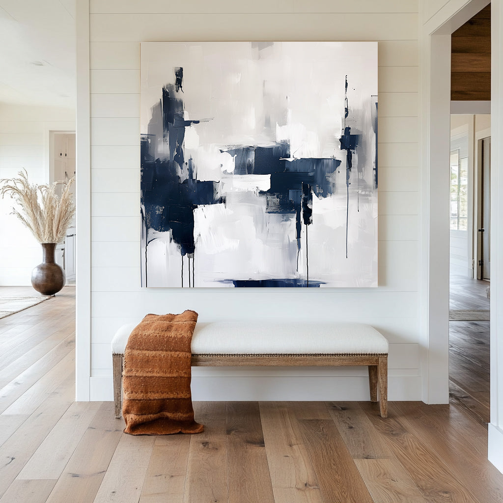 Abstract wall artwork featuring bold navy and white brushstrokes with dripped accents on a textured background.