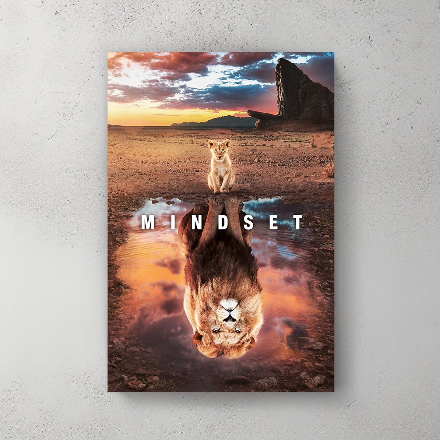 A motivational wall art print of a lion cub looking into a reflection pool, revealing a lion's image, set against a dramatic sunset and savannah landscape.