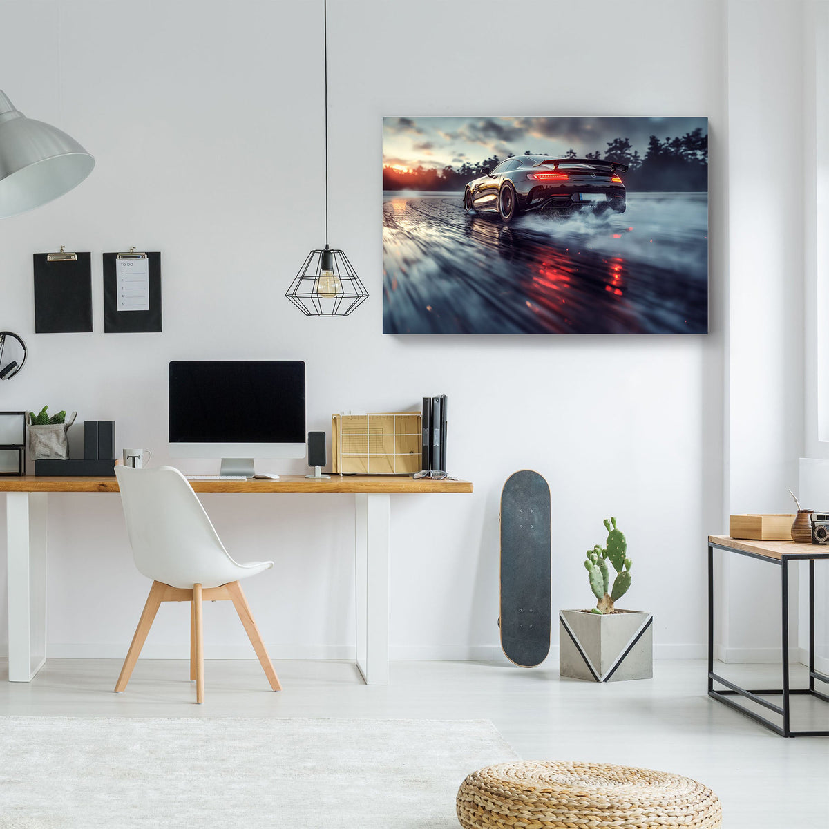 A rectangular wall art print showing a sports car driving on wet asphalt at sunset, displayed in a modern home office setting above a desk with a white chair.