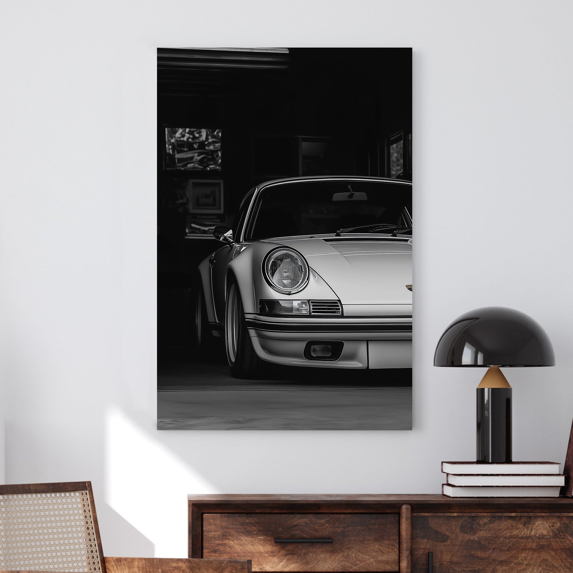 A black-and-white digital wall art print of a silver Porsche emerging from the shadows of a dimly lit garage, showcasing its refined curves and elegance.