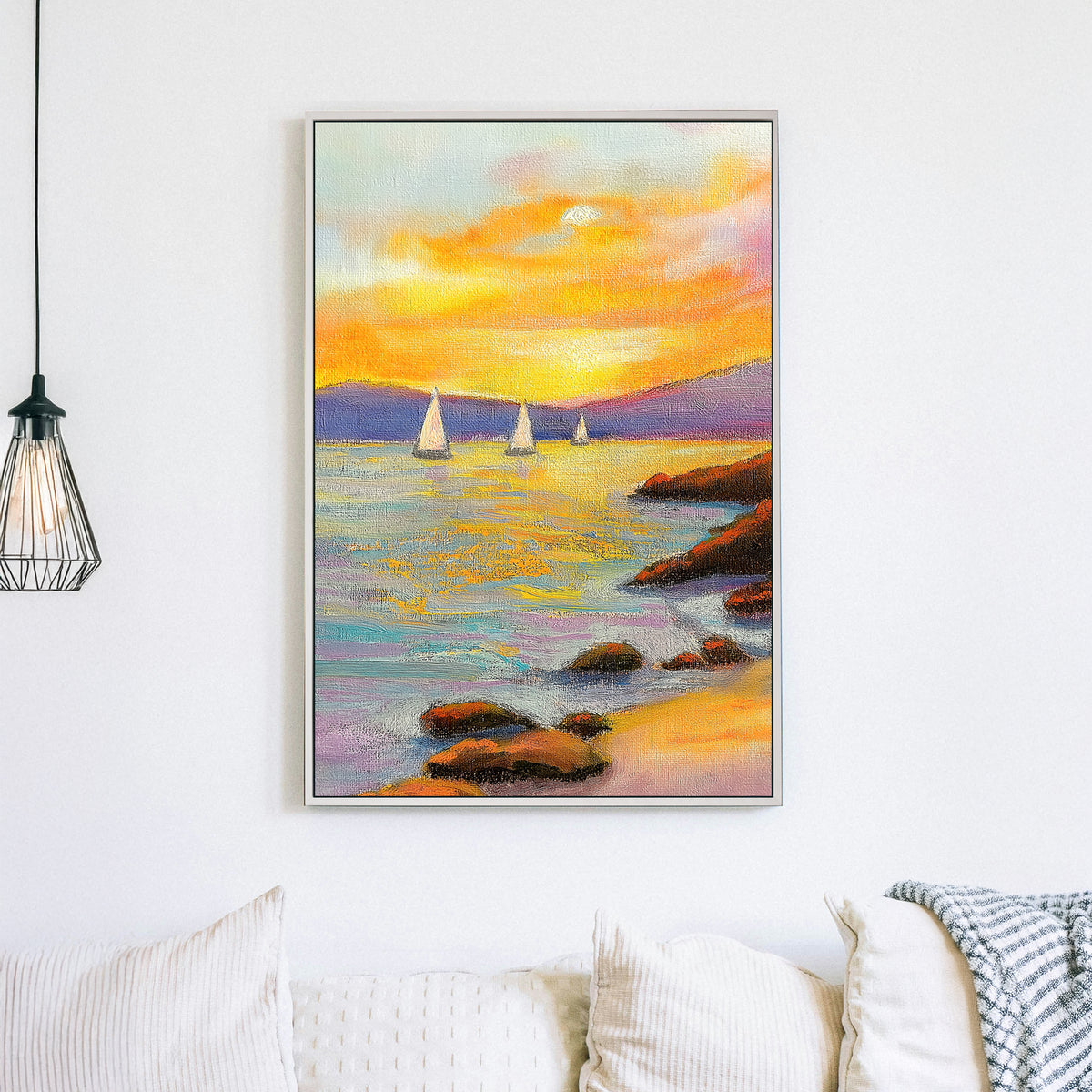 Vivid oil wall art of a sunset over the ocean, with sailboats in the distance and a rocky shoreline in the foreground.