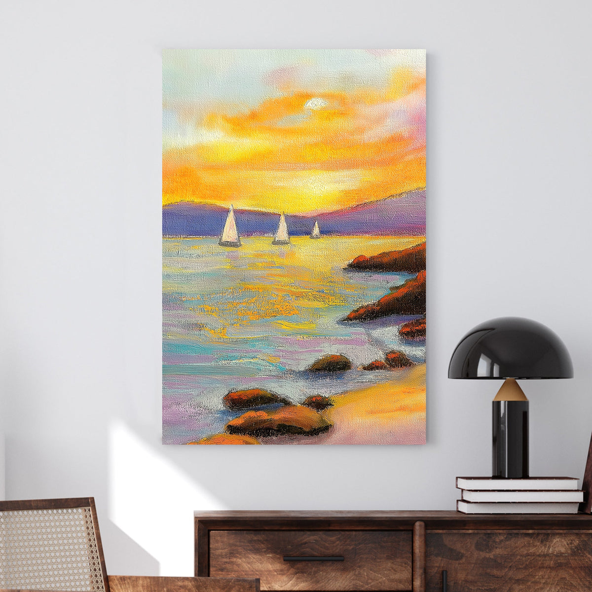 Vivid oil wall art of a sunset over the ocean, with sailboats in the distance and a rocky shoreline in the foreground.