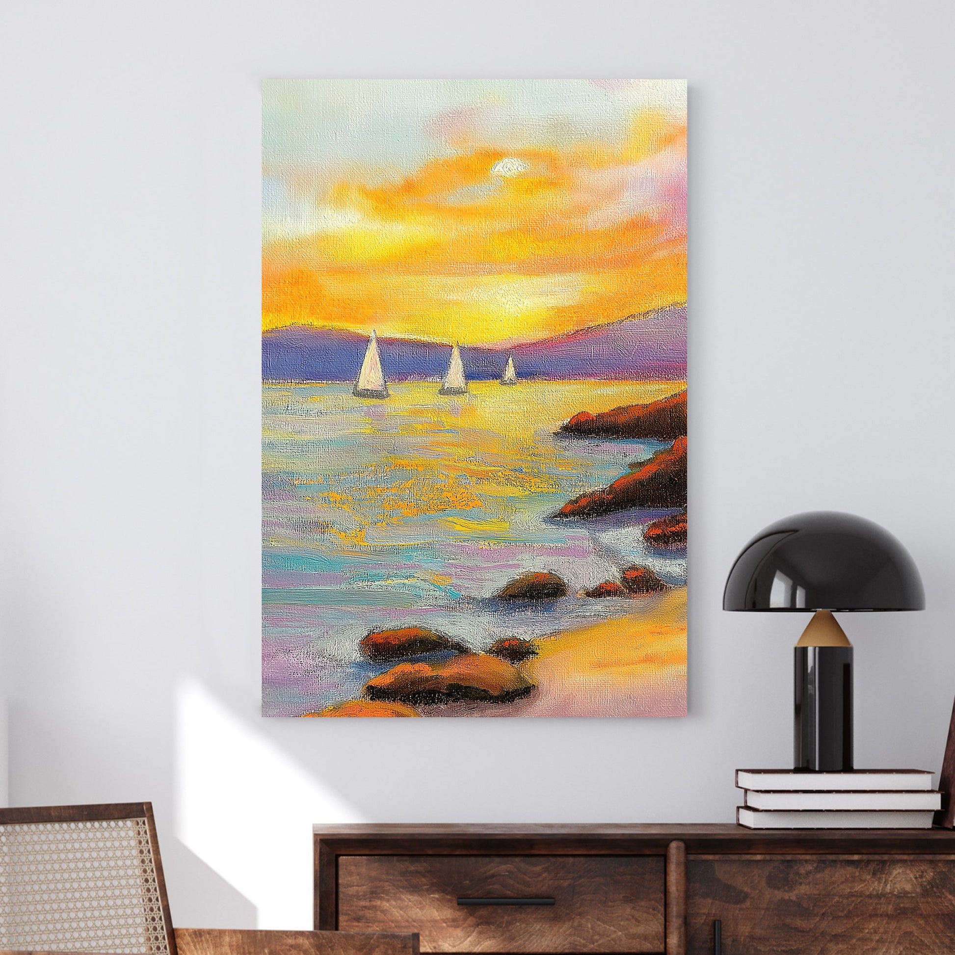 Vivid oil wall art of a sunset over the ocean, with sailboats in the distance and a rocky shoreline in the foreground.