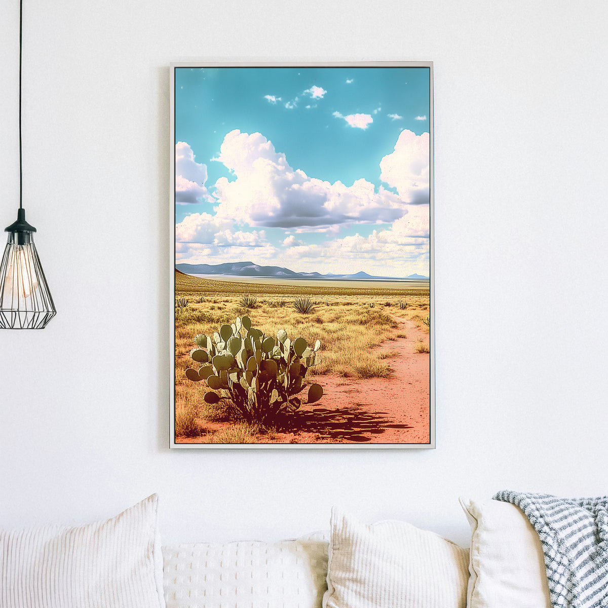 Vintage-style desert landscape with a prickly pear cactus, golden sand, distant mountains, and a vast blue sky filled with fluffy clouds.