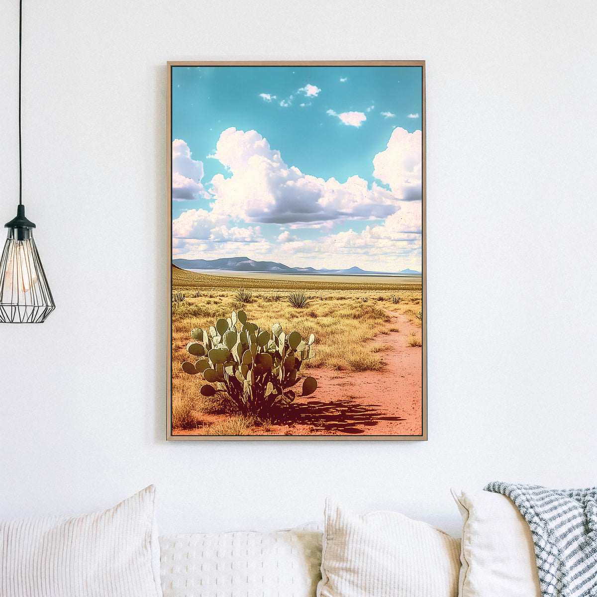 Vintage-style desert landscape with a prickly pear cactus, golden sand, distant mountains, and a vast blue sky filled with fluffy clouds.
