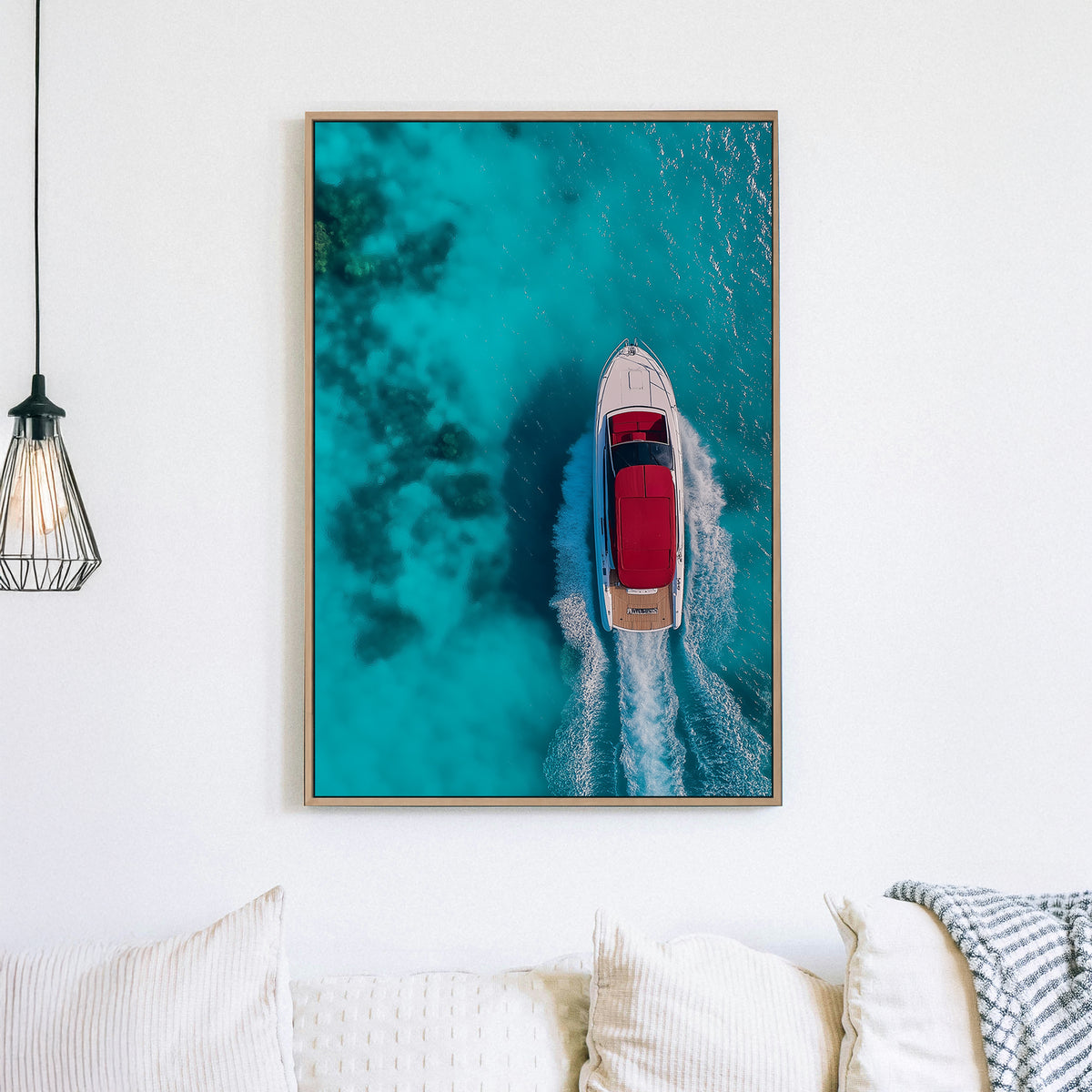 Aerial view of a white yacht with a red canopy cruising through turquoise ocean waters, leaving a foamy wake.
