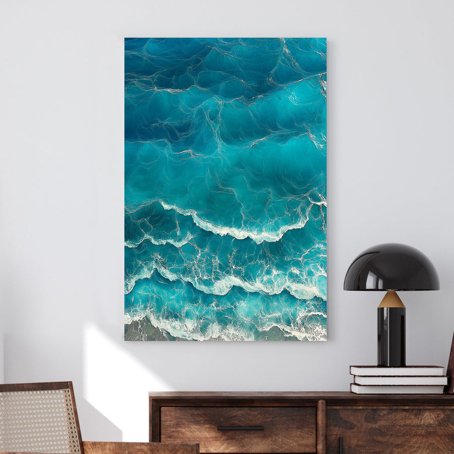 Aerial view of ocean waves rolling onto the shore, featuring deep blue hues and white foamy textures.