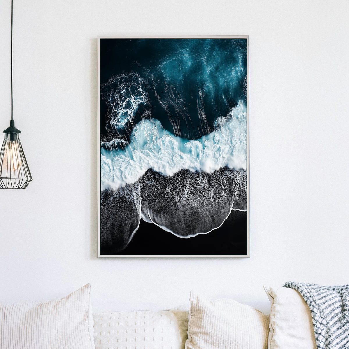 Aerial ocean wall art with deep blue waves crashing onto a black sand beach.