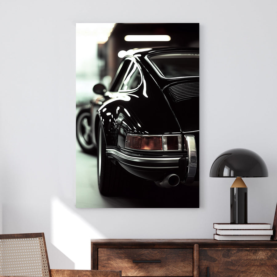 Close-up of a classic black Porsche with reflective chrome details in a dimly lit garage.