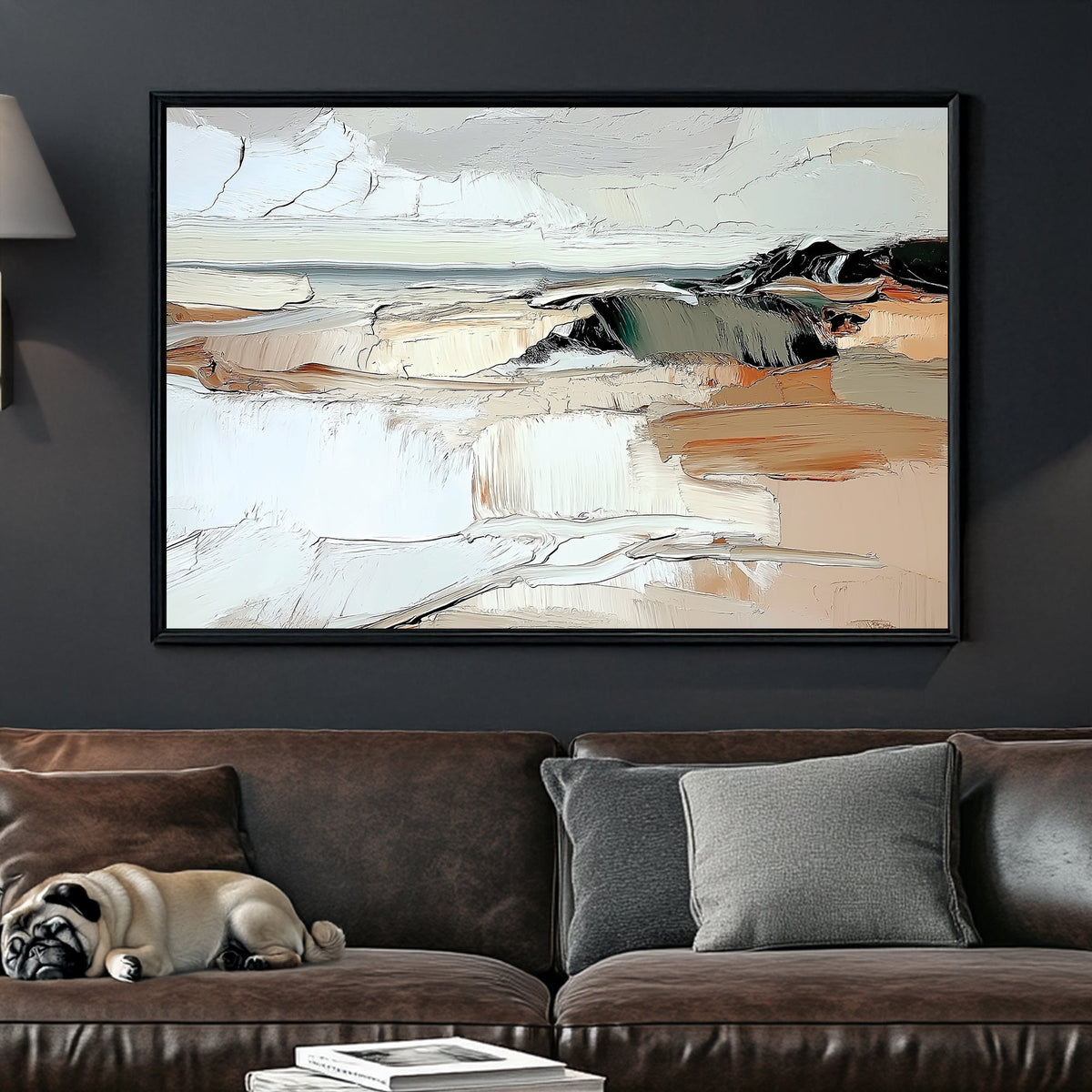A framed abstract landscape painting with cream, beige, gray, and black brushstrokes hangs on a dark gray wall above a brown leather sofa with pillows and a sleeping pug.