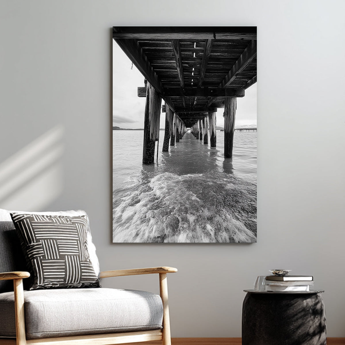 black and white wall art photography of ocean waves under wooden pier with vanishing point perspective