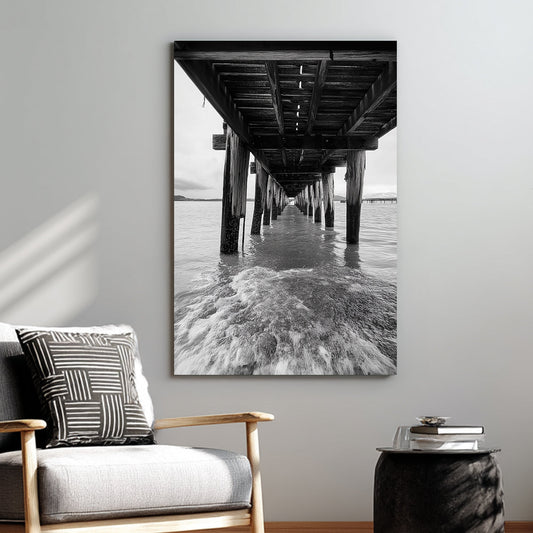 black and white wall art photography of ocean waves under wooden pier with vanishing point perspective