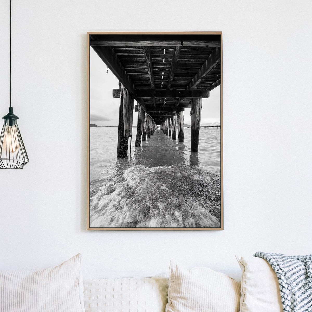 black and white wall art photography of ocean waves under wooden pier with vanishing point perspective