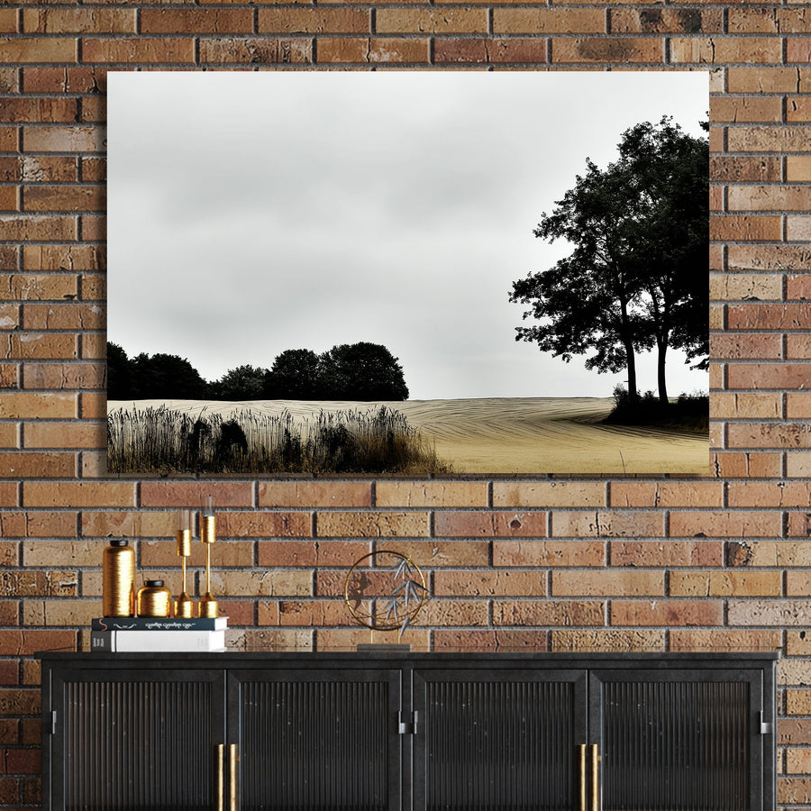 moody rural landscape with trees and curved farmland under grey sky wall art