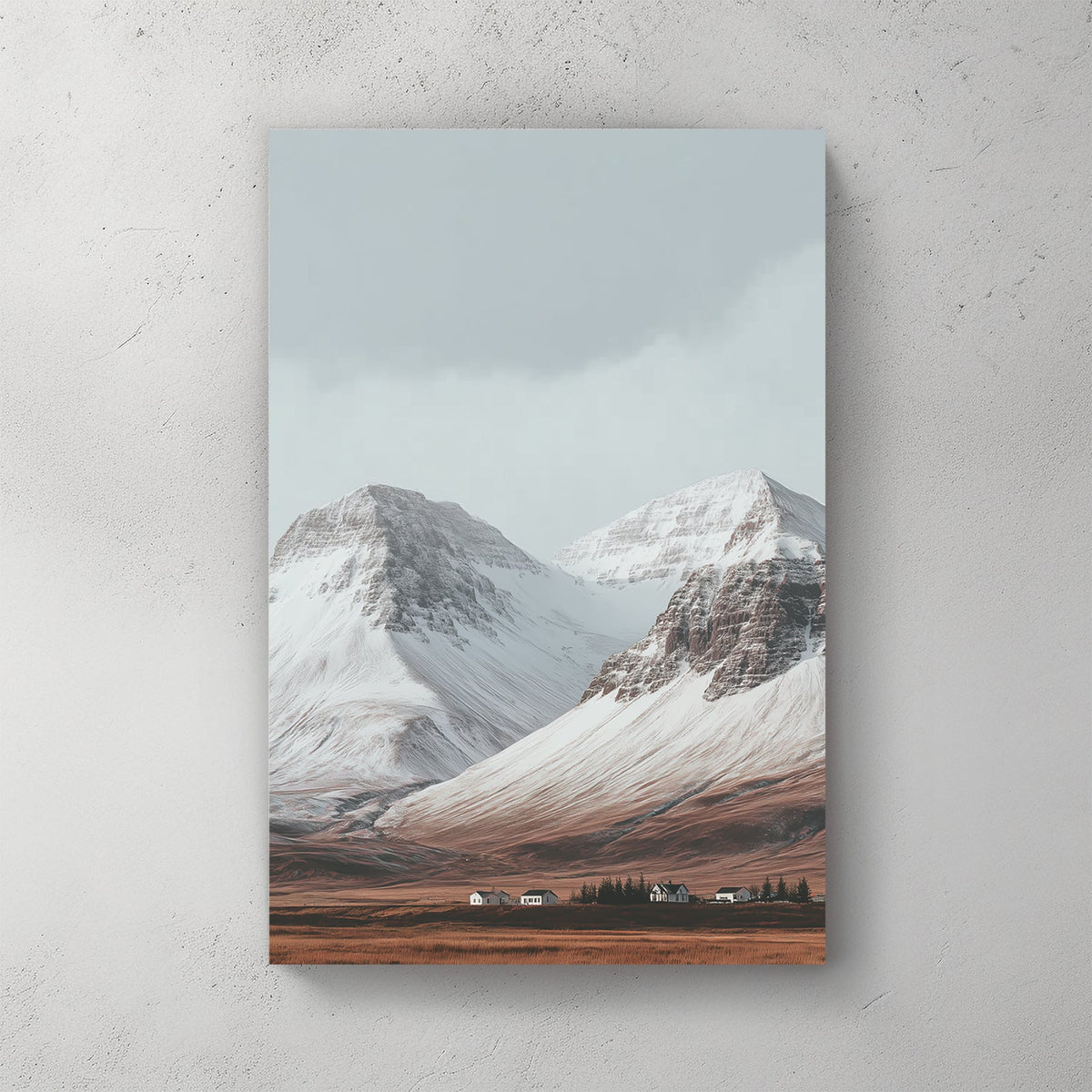 Snowy mountain landscape with cabins on a golden plain beneath grey skies