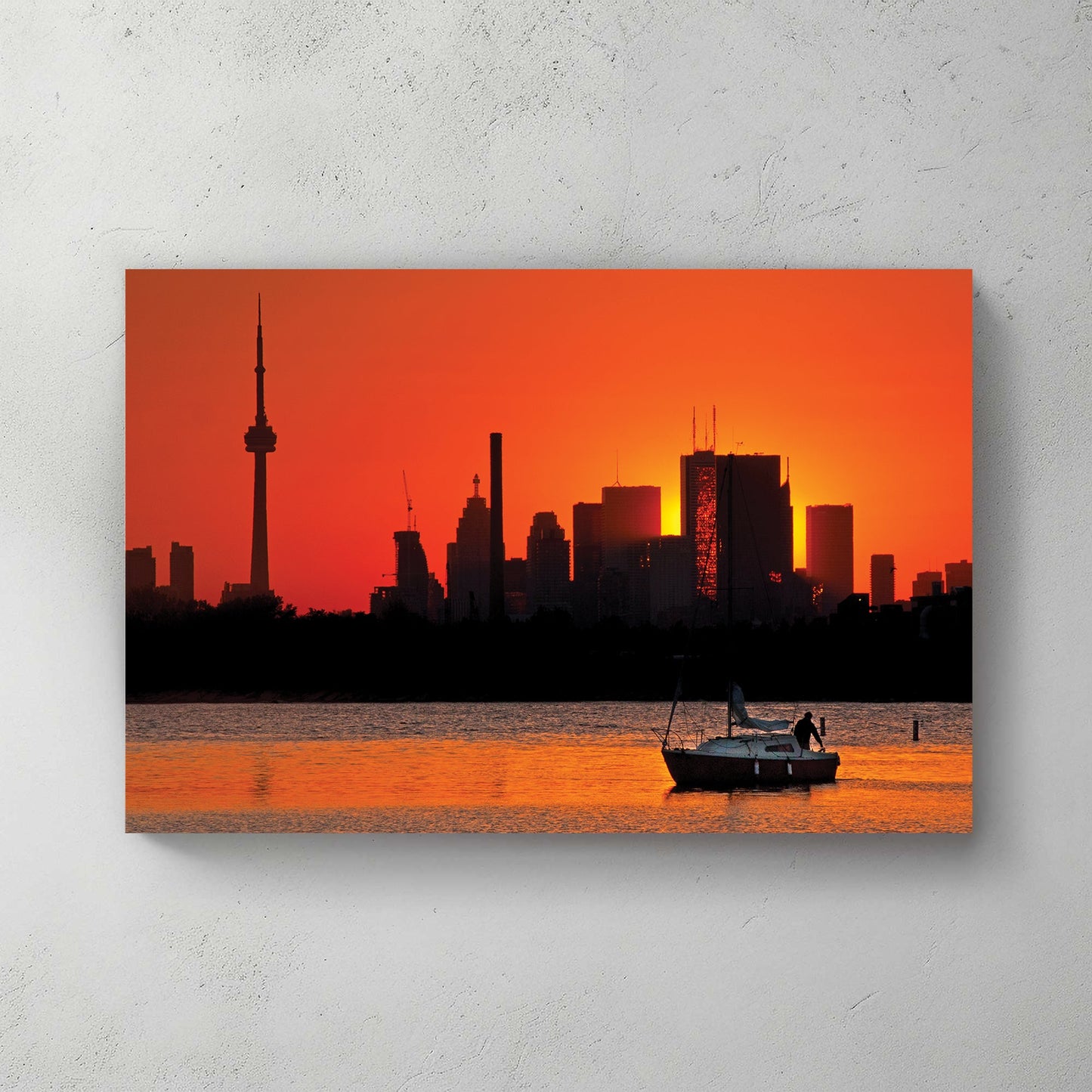 Toronto skyline at sunset with sailboat on water at Ashbridges Bay