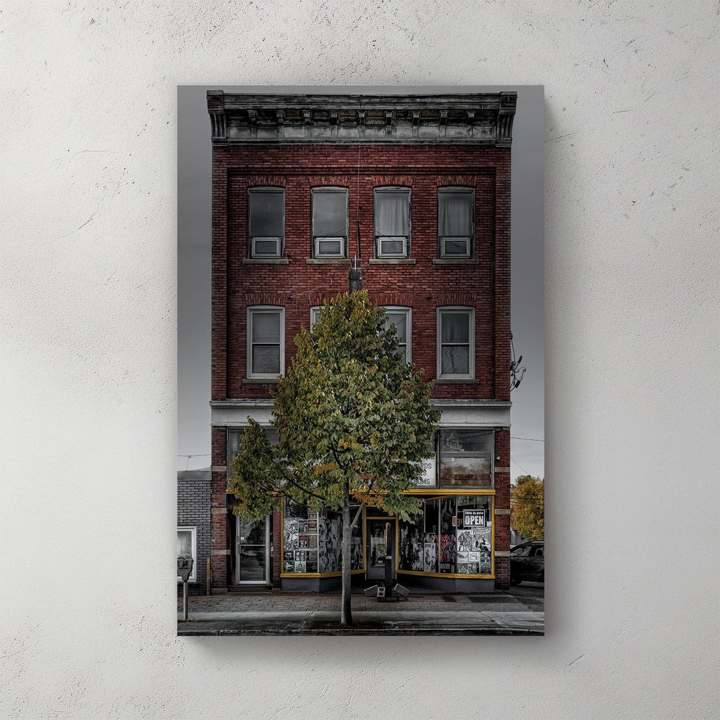 Vintage red-brick storefront with urban posters and single tree, moody sky backdrop