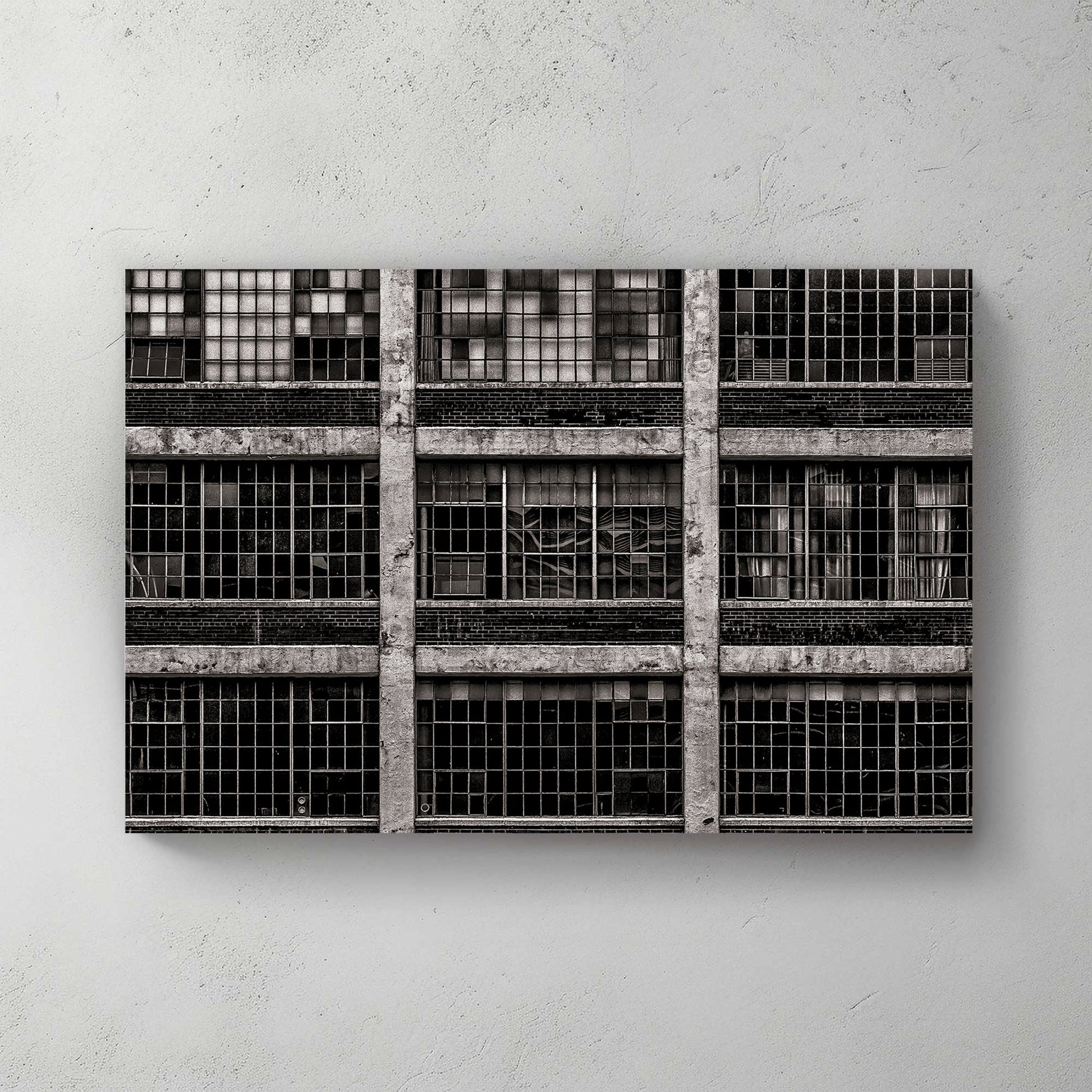 black and white industrial building with broken window panes and symmetrical grid layout