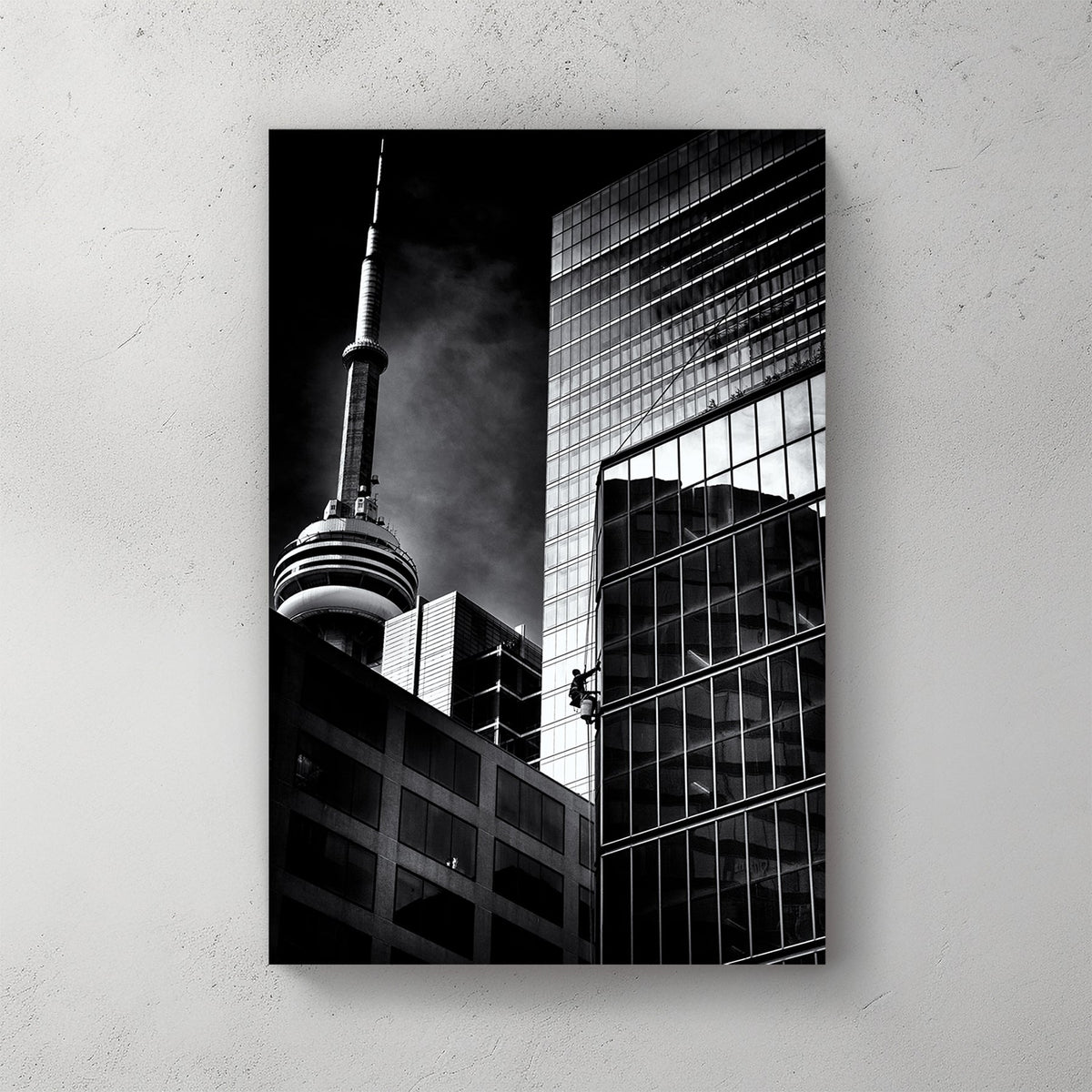 black and white photo of CN Tower and window washer on Toronto skyscraper