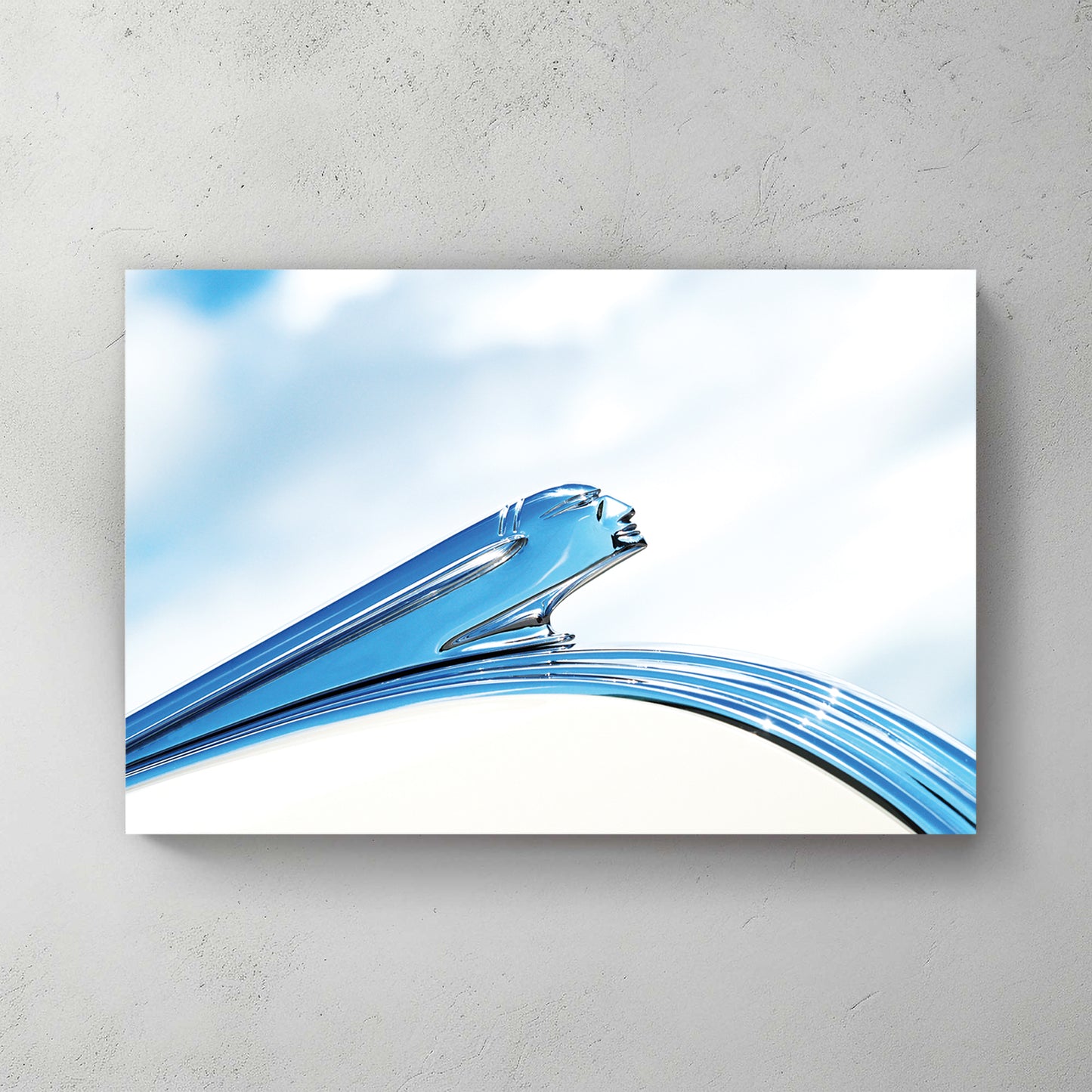 Art Deco chrome Pontiac hood ornament, a streamlined winged figure in polished silver against soft blue sky and cloud — canvas wall art print