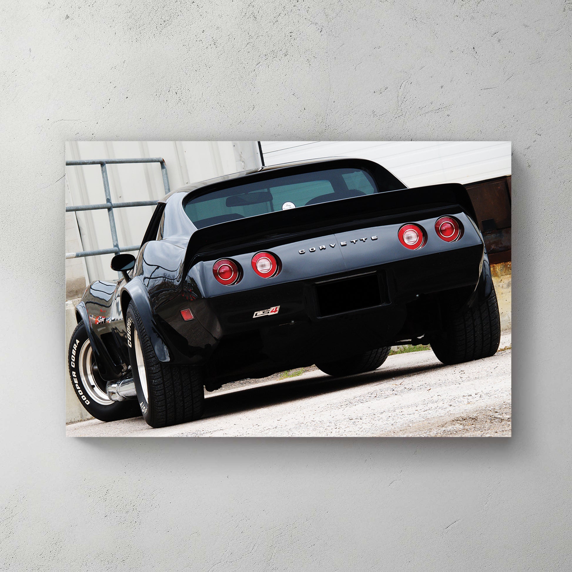 Glossy black C3 Corvette rear, round red taillights and chrome CORVETTE script, parked on gravel — canvas wall art print