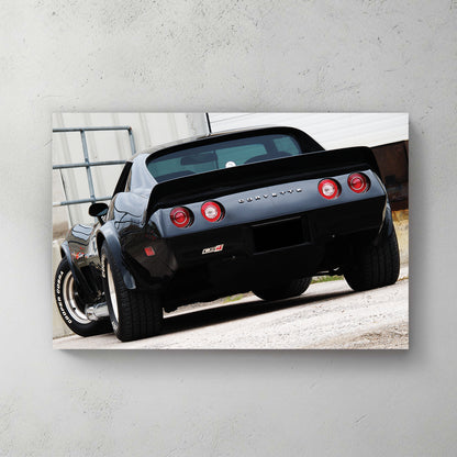 Glossy black C3 Corvette rear, round red taillights and chrome CORVETTE script, parked on gravel — canvas wall art print