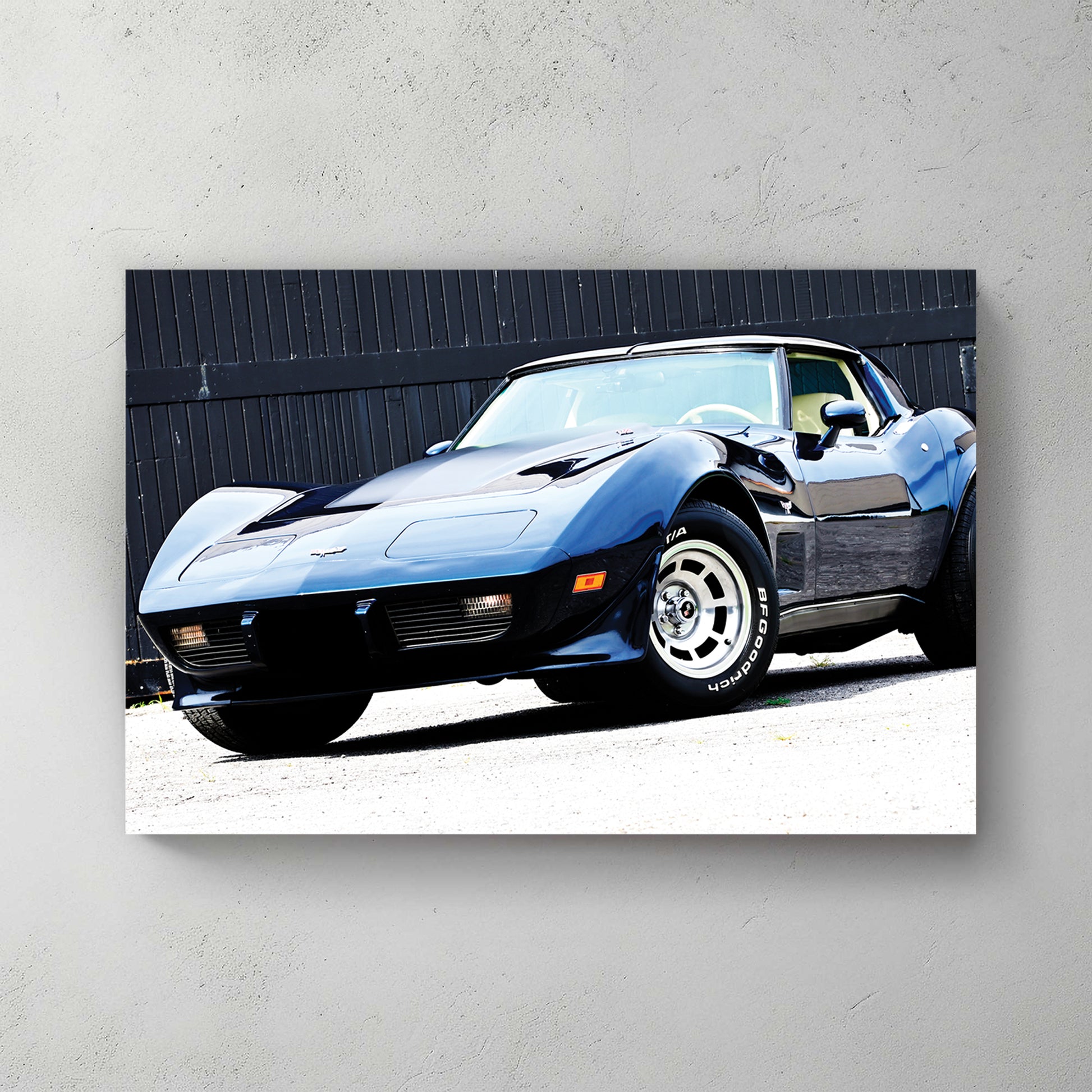 Dark blue C3 Corvette front three-quarter against black barn doors, hard sun, muscular fenders — canvas wall art print