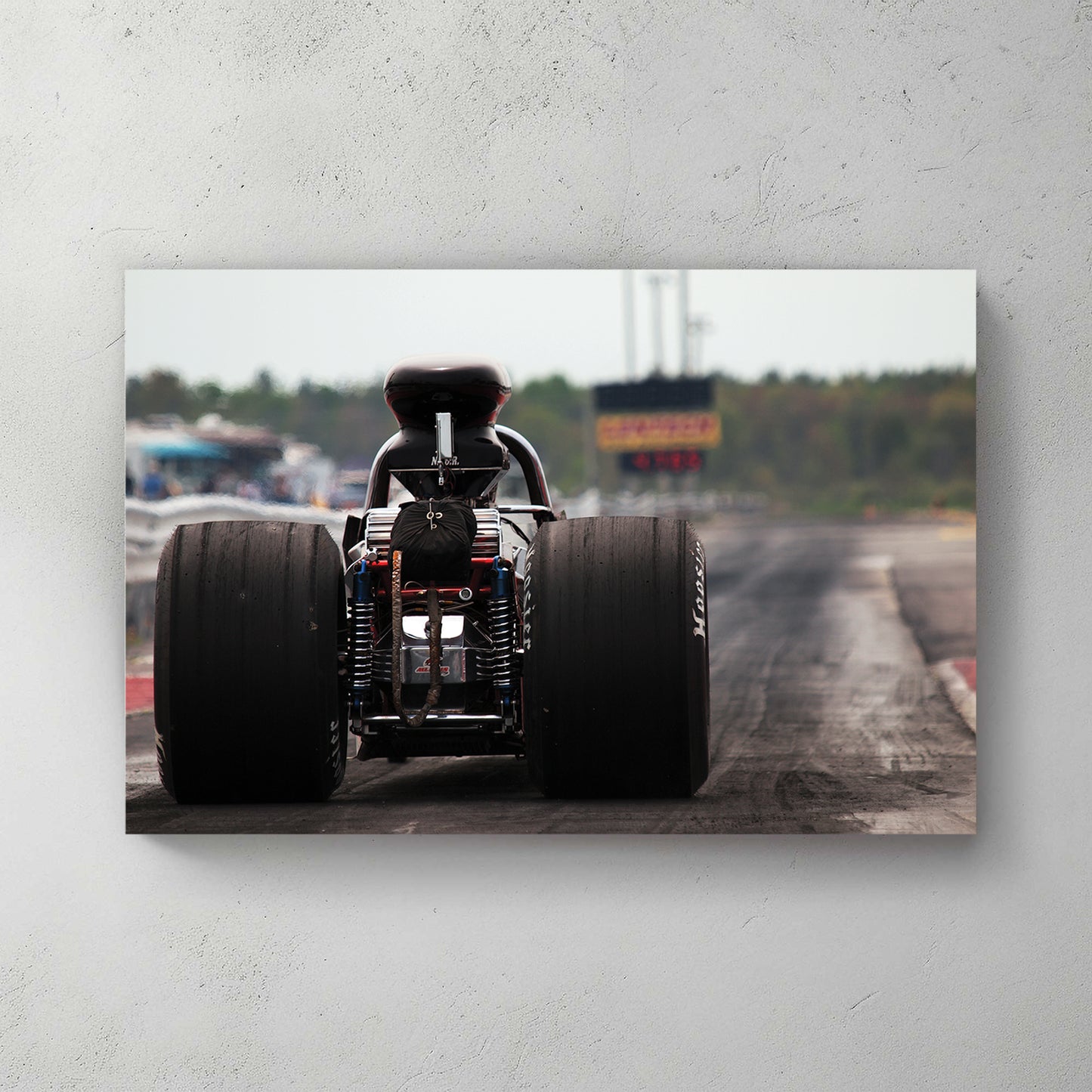 Rear-engine dragster staged on the strip, huge Hoosier slicks, chrome headers, grandstands behind — canvas wall art print