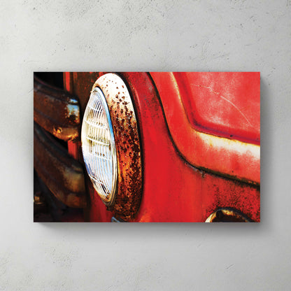 Sun-hit close-up of a rusty red vintage fire truck, patina around a chrome headlight ring — canvas wall art print