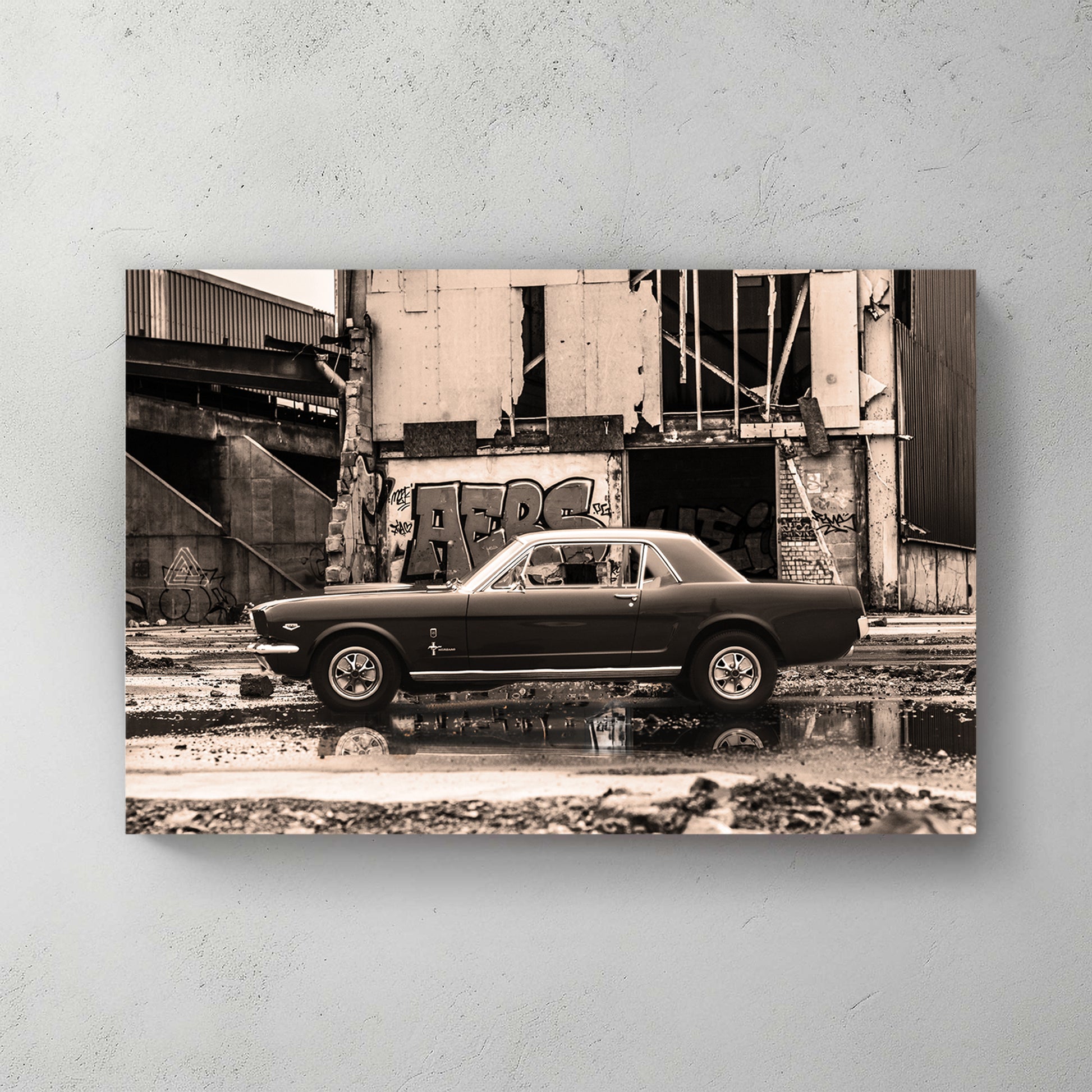 Sepia-toned classic Mustang parked before a graffiti-covered abandoned industrial building, puddle reflection — canvas wall art print