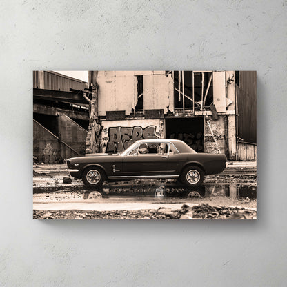 Sepia-toned classic Mustang parked before a graffiti-covered abandoned industrial building, puddle reflection — canvas wall art print