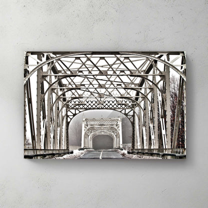 Symmetrical view down a white lattice steel truss bridge, snow-lined edges vanishing into winter fog — canvas wall art print