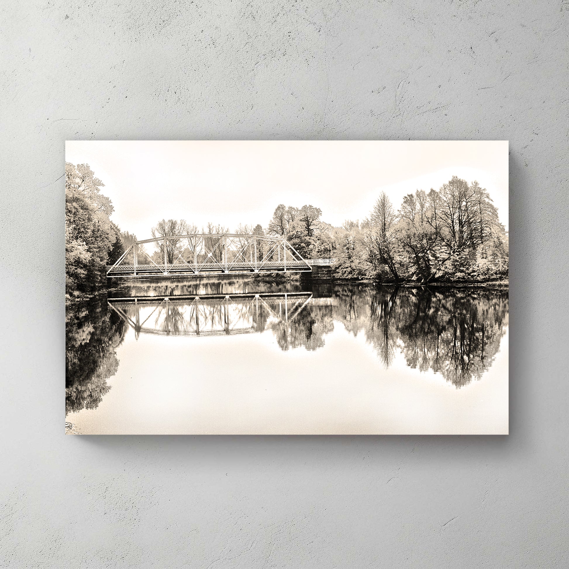Sepia truss bridge mirrored in glass-calm water, soft trees framing both banks — canvas wall art print