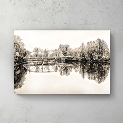 Sepia truss bridge mirrored in glass-calm water, soft trees framing both banks — canvas wall art print