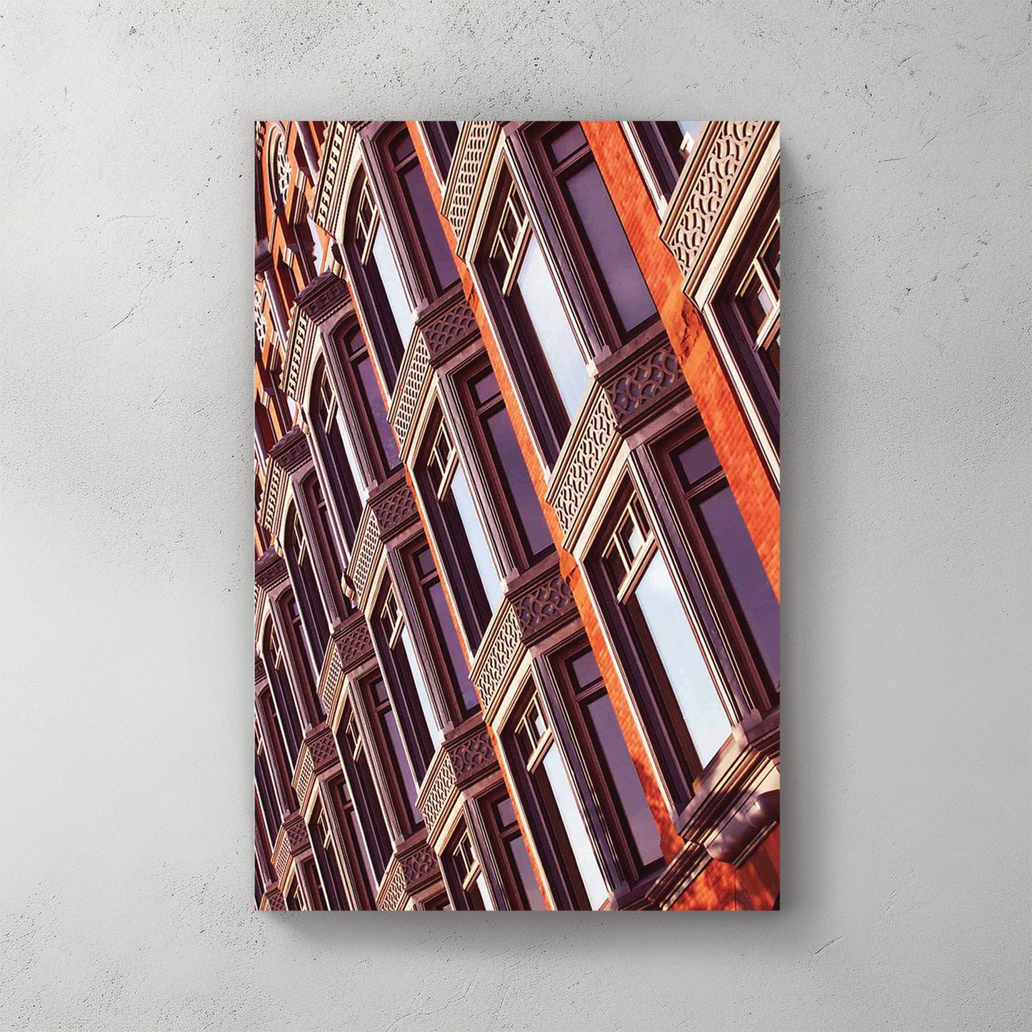 Warm-lit angled view of an ornate red-brick heritage building, carved bay windows and patterned stone — canvas wall art print