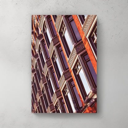 Warm-lit angled view of an ornate red-brick heritage building, carved bay windows and patterned stone — canvas wall art print