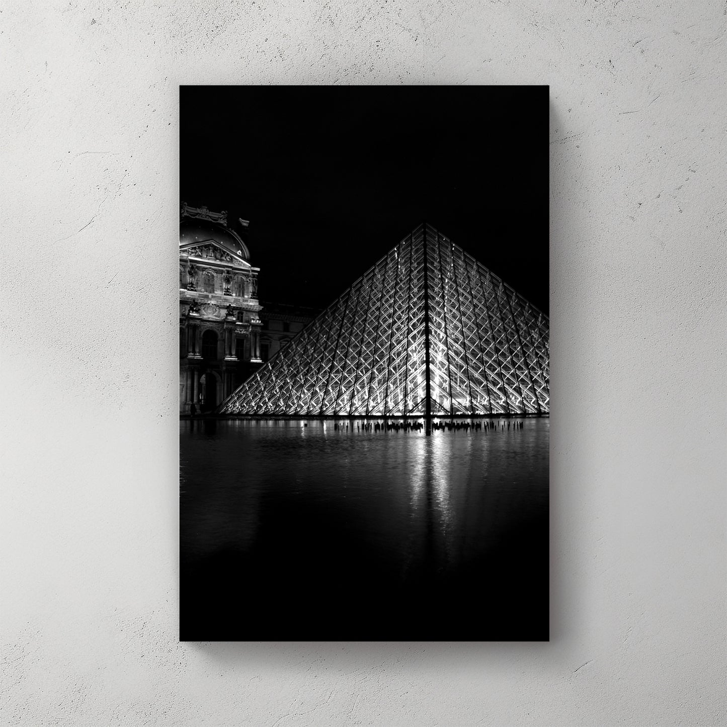 Black-and-white Louvre glass pyramid lit at night, mirrored in the courtyard pool beside the old palace — canvas wall art print